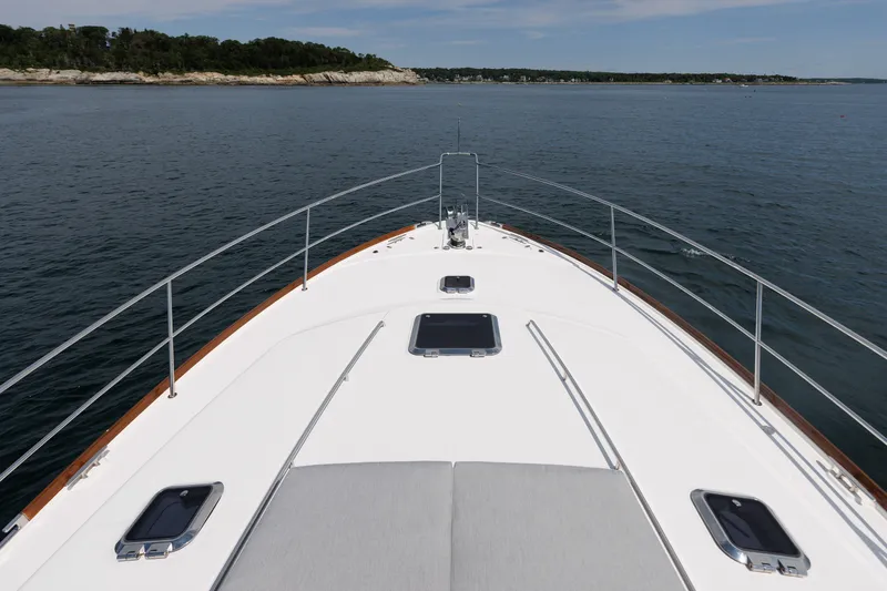 Slide: The Image of 2024 Sabre 48 Salon Express yacht cruising on calm waters near a rocky shoreline. - 9