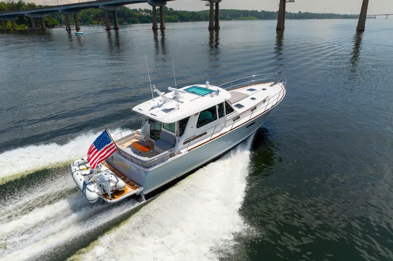 The Image of 2024 Sabre 48 Salon Express cruising under a bridge on a calm river. - 0