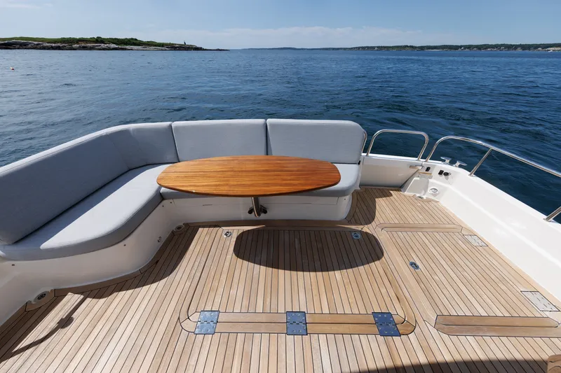 Slide: The Image of 2024 Sabre 48 Salon Express yacht deck with seating and wooden table, ocean view. - 12