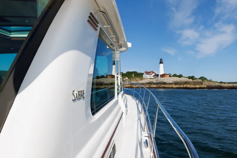 Slide: The Image of 2024 Sabre 48 Salon Express yacht cruising near a scenic lighthouse on a sunny day. - 1