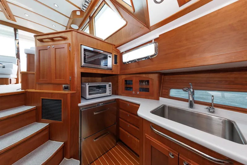 Slide: The Image of Luxurious 2024 Sabre 48 Salon Express yacht interior with modern kitchen amenities and elegant wood finish. - 16