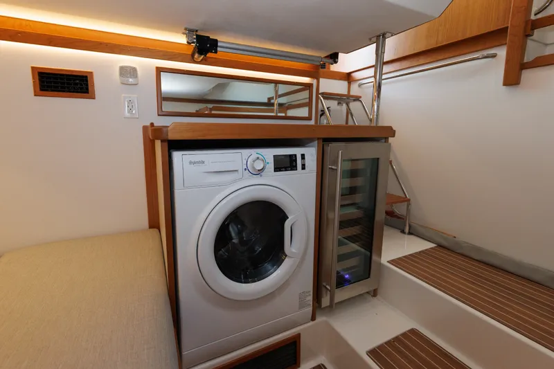 Slide: The Image of 2024 Sabre 48 Salon Express interior with washer and mini fridge, featuring wooden accents. - 36