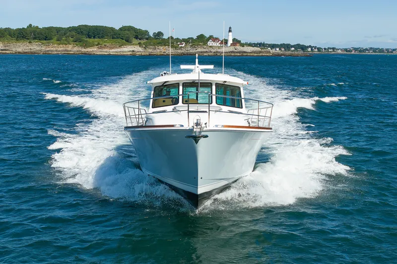 Slide: The Image of 2024 Sabre 48 Salon Express cruising on open water near a scenic coastline. - 7