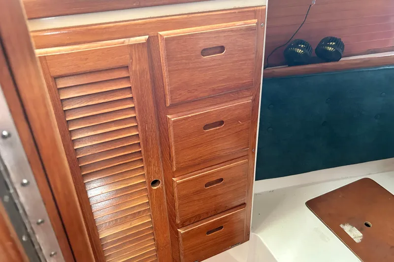 Slide: The Image of Wooden cabinetry inside a 1998 Catalina 36 MkII sailboat, featuring drawers and a louvered door. - 49