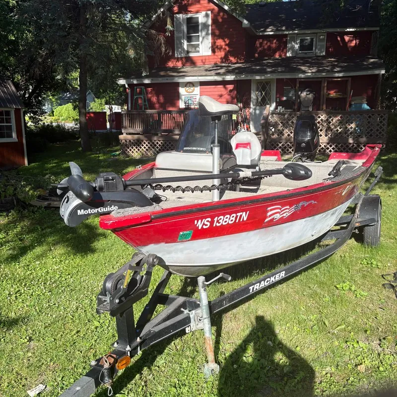 The Image of A red 2013 Tracker boat on a trailer in front of a house. - 0