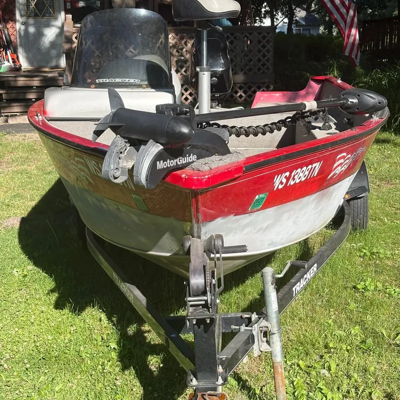 Slide: The Image of A red Tracker boat on a trailer in the grass, featuring a MotorGuide motor. - 12