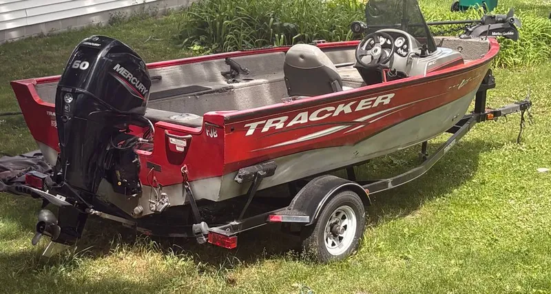 Slide: The Image of A red 2013 Tracker boat on a trailer in the grass. - 2