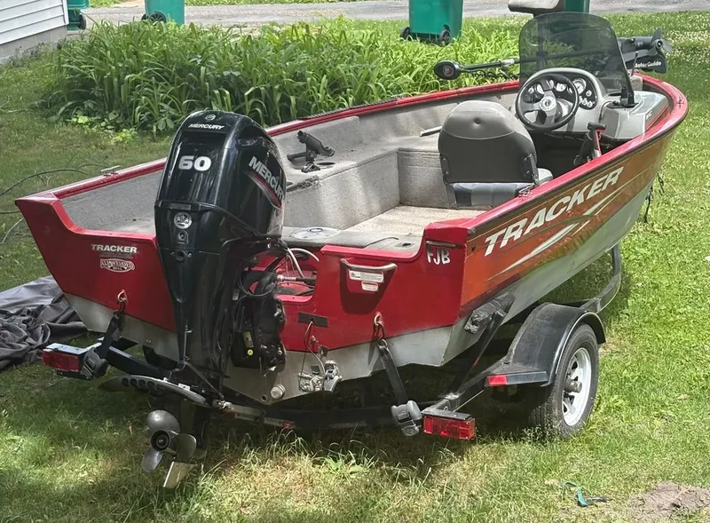 Slide: The Image of A red 2013 Tracker boat sits on a trailer on grass. - 13