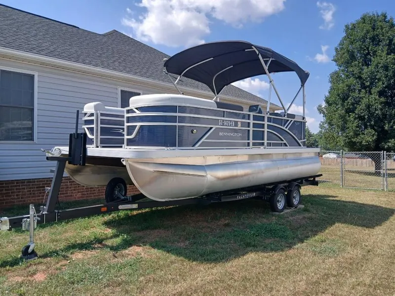 Slide: The Image of A Bennington 20SL pontoon boat is on a trailer next to a house. - 2