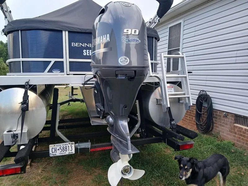 Slide: The Image of A Bennington 20SL pontoon boat with a Yamaha 90 outboard motor, on a trailer next to a house. - 30