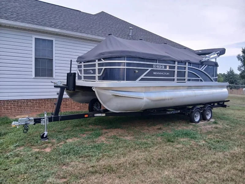 Slide: The Image of A 2026 Bennington 20SL pontoon boat on a trailer beside a house. - 3