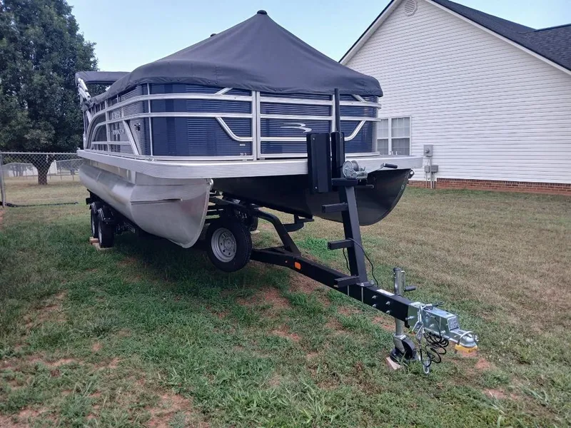 Slide: The Image of A 2026 Bennington 20SL pontoon boat on a trailer, parked on a grassy area. - 1