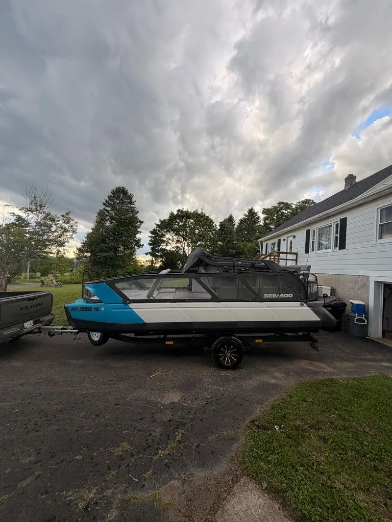 The Image of A 2023 Sea-Doo Switch Sport on a trailer in a driveway, surrounded by trees. - 0