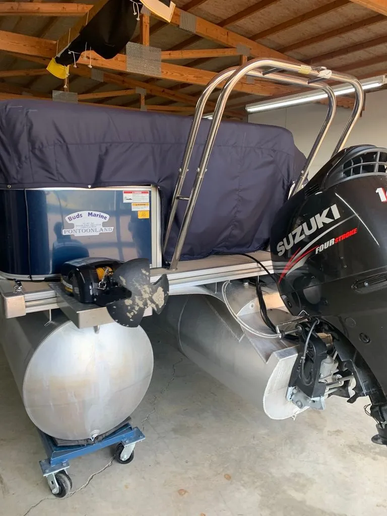 Slide: The Image of A 2011 Sylvan 8520 Cruise pontoon boat with a Suzuki outboard motor in a garage. - 19