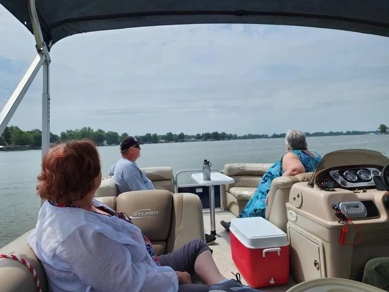 Slide: The Image of Three people relax on a pontoon boat on a calm lake. - 10