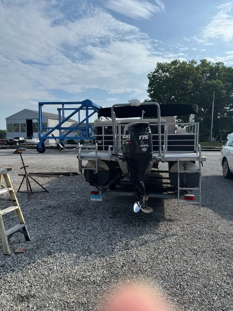 Slide: The Image of A 2014 Bentley Pontoons Elite 25 on a gravel lot. A Suzuki 175 outboard motor is visible. - 13
