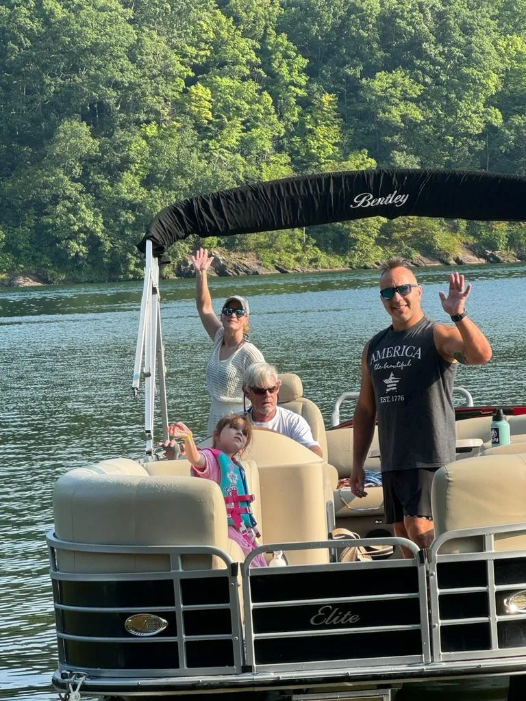 Slide: The Image of A family waves from a Bentley Pontoons Elite 25 on a calm lake. - 3