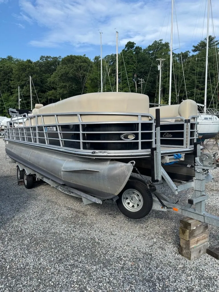 Slide: The Image of A 2014 Bentley Pontoons Elite 25 on a trailer in a gravel lot. - 1