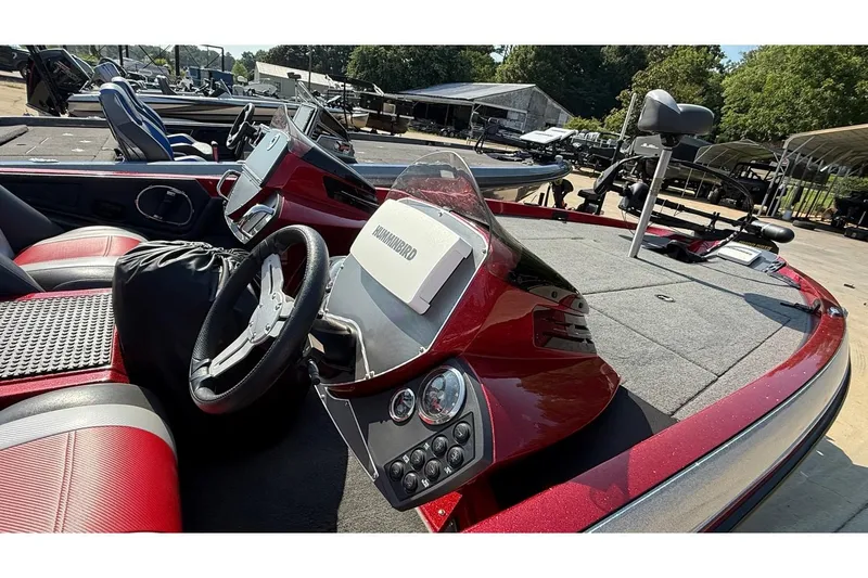 Slide: The Image of 2014 Ranger Z118 Comanche boat interior with steering wheel and dashboard, featuring red and gray seating. - 12