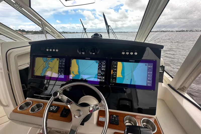 Slide: The Image of Cockpit of 2024 Boston Whaler 380 Realm with navigation screens and steering wheel. - 13