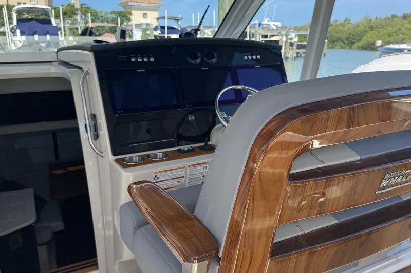 Slide: The Image of 2024 Boston Whaler 380 Realm helm with modern controls and luxurious seating. - 11