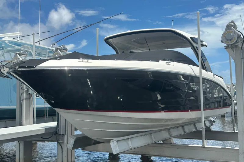 The Image of 2020 Sea Ray SLX 350 Outboard boat on lift, under clear blue sky. - 0