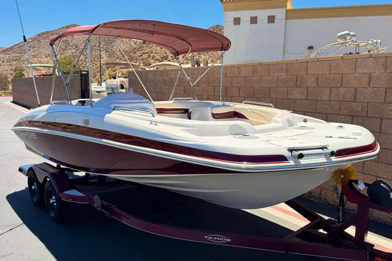 Slide: The Image of 2010 Tahoe 195 boat with maroon accents on a trailer, set against a sunny backdrop. - 1