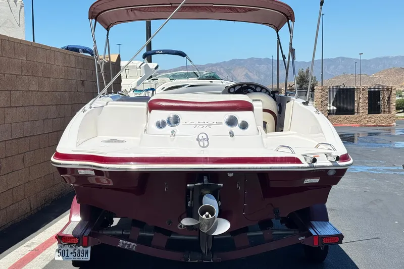 Slide: The Image of 2010 Tahoe 195 boat with canopy, parked on a trailer, rear view. - 4