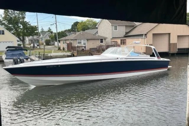 Slide: The Image of 1990 Cary 50 boat on a calm canal near residential homes. - 1