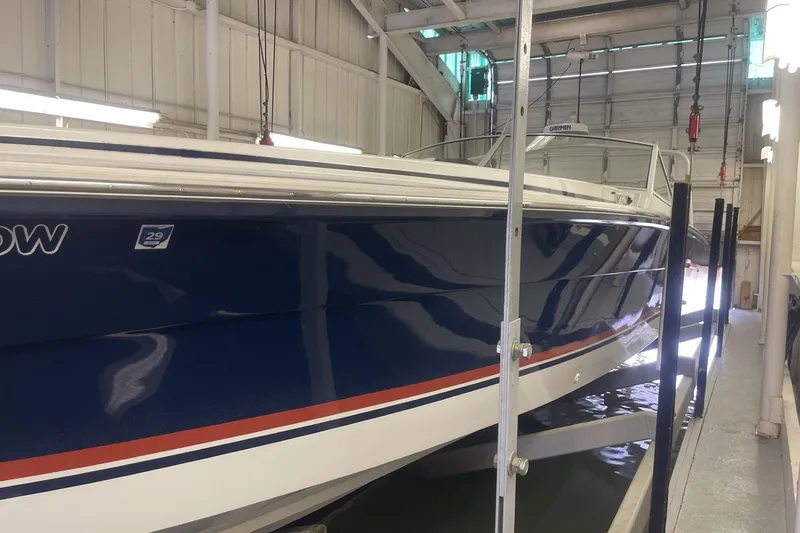 Slide: The Image of 1990 Cary 50 boat in storage, blue hull with red and white stripes, indoor facility. - 2