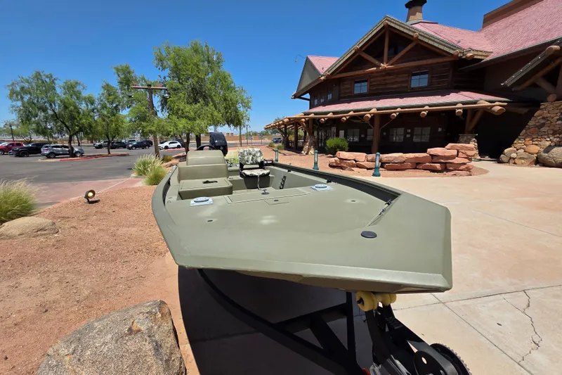 Slide: The Image of 2024 Tracker Grizzly 1754 SC boat displayed outdoors near rustic building. - 9