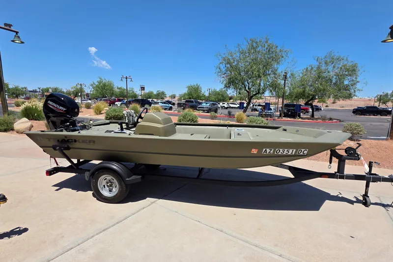 Slide: The Image of 2024 Tracker Grizzly 1754 SC boat on trailer, parked outdoors under clear blue sky. - 6