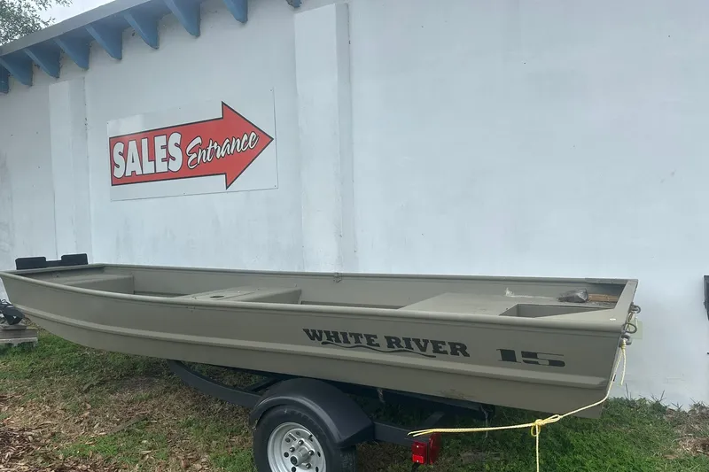 Slide: The Image of 2025 White River TOPPER 1542 Jon Boat on trailer near sales entrance sign. - 1