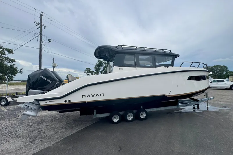 Slide: The Image of Navan C30 2026 boat on trailer, side view, parked outdoors under cloudy sky. - 1