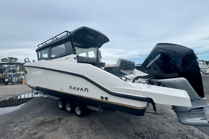 Slide: The Image of 2026 Navan C30 boat with Mercury engine, parked on a trailer, under a cloudy sky. - 7