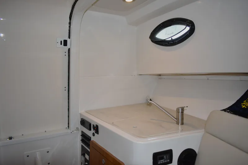 Slide: The Image of Interior of 2020 Sailfish 270 WAC boat featuring a compact kitchenette with sink. - 17