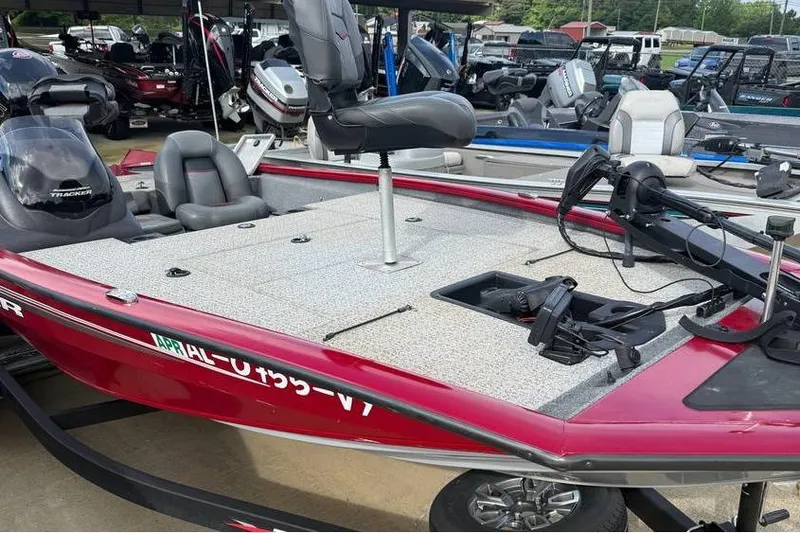The Image of 2024 Tracker Pro Team 195 TXW Tournament Edition boat, red exterior, docked with fishing equipment. - 0