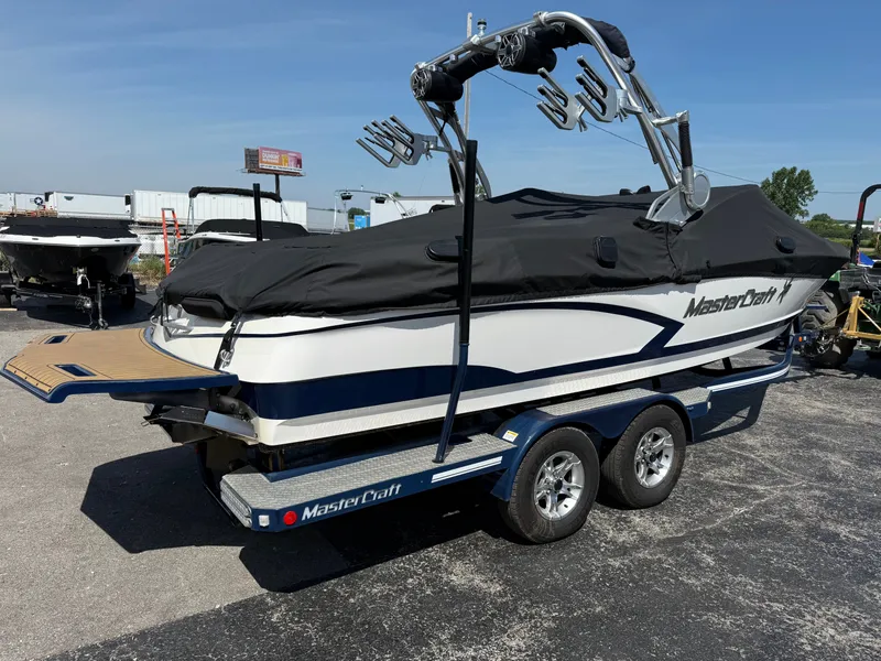 Slide: The Image of 2016 MasterCraft X30 on a trailer, with cover and tower, in a parking lot. - 5