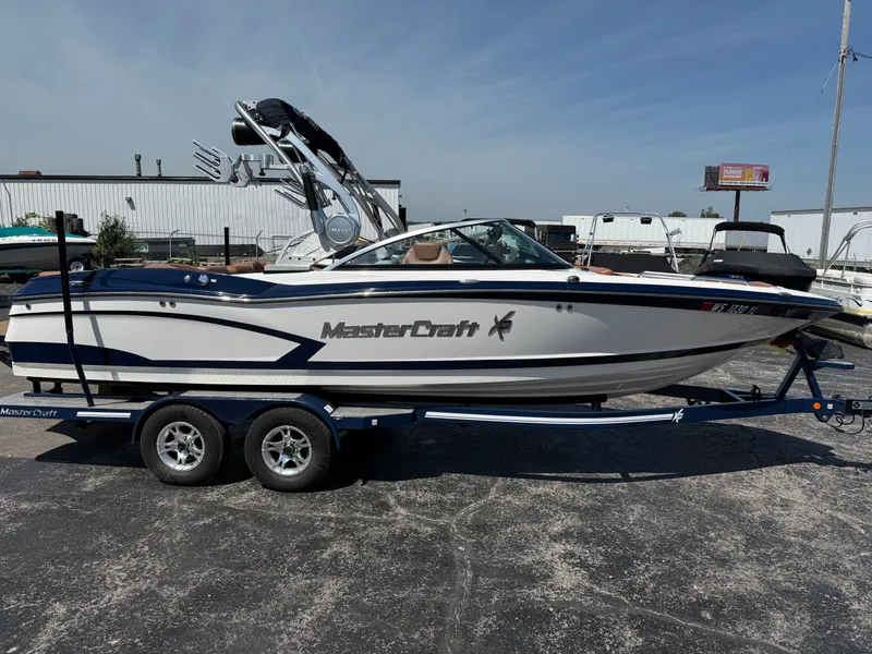 Slide: The Image of A 2016 MasterCraft X30 boat on a trailer, featuring a tower and blue accents. - 12