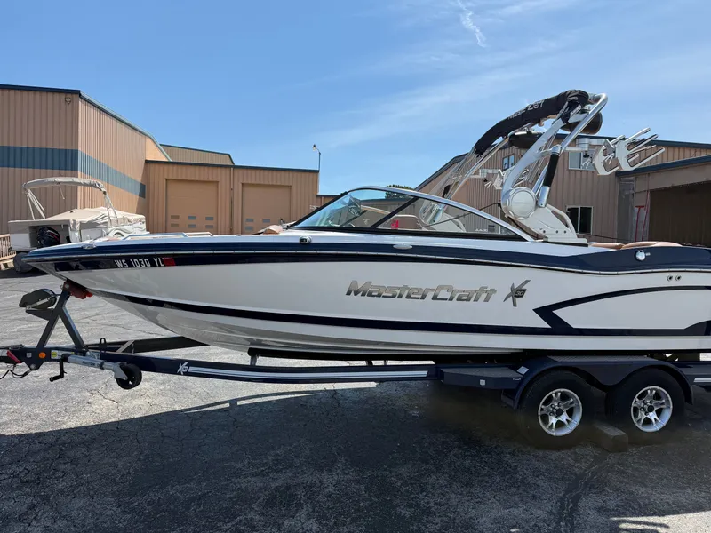 Slide: The Image of A 2016 MasterCraft X30 boat on a trailer, parked in front of a warehouse. - 17