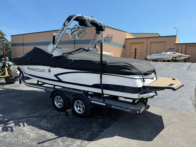 Slide: The Image of A 2016 MasterCraft X30 on a trailer, covered, in front of a warehouse building. - 3