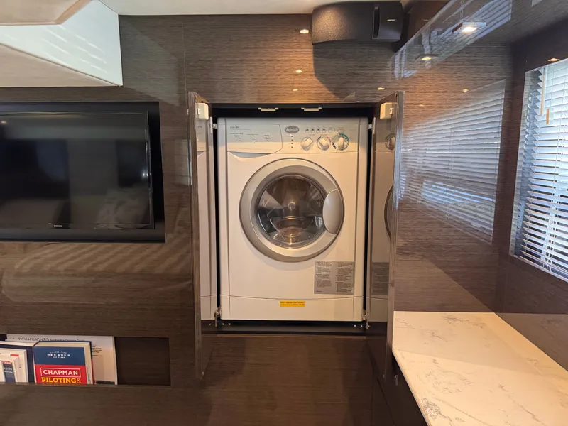 Slide: The Image of A modern washer-dryer in a sleek, wood-paneled room with a TV and bookshelf. - 25
