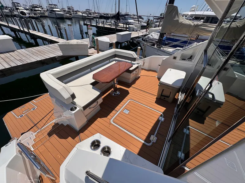 Slide: The Image of The image shows the aft deck of a 2021 Cruisers Yachts 50 Cantius with elegant seating and a wooden table. - 4