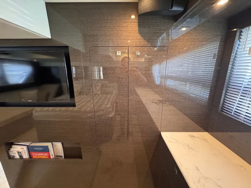 Slide: The Image of Interior of a modern yacht with glossy walls, a TV, and a shelf with books. - 24
