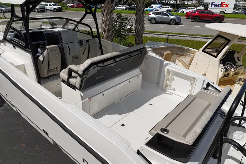 Slide: The Image of 2026 Navan S30 boat interior with seating and storage, parked near a road with passing vehicles. - 8