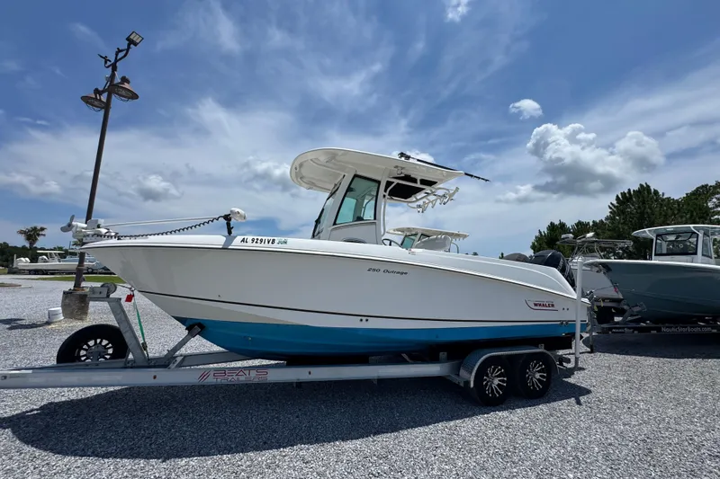 Slide: The Image of 2014 Boston Whaler 250 Outrage boat on trailer under a clear blue sky. - 2