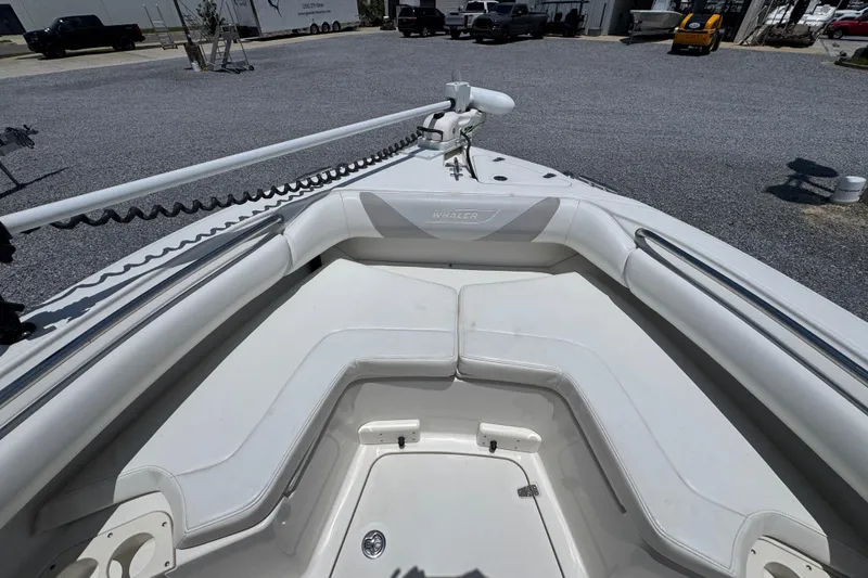 Slide: The Image of 2014 Boston Whaler 250 Outrage boat interior with white cushioned seating and storage compartment. - 17