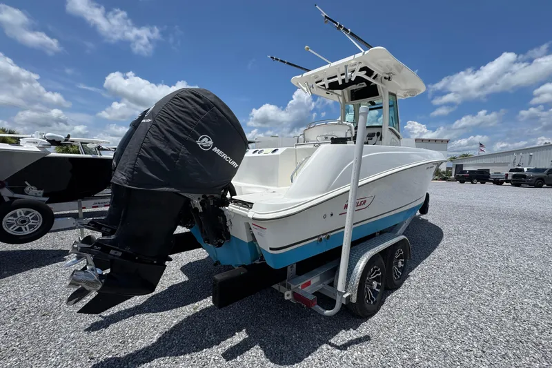 Slide: The Image of 2014 Boston Whaler 250 Outrage boat on trailer, featuring Mercury engine, under clear blue sky. - 11