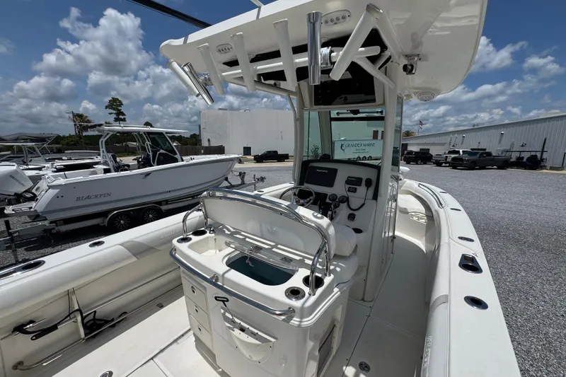 Slide: The Image of 2014 Boston Whaler 250 Outrage boat interior with console and seating, parked outdoors. - 35