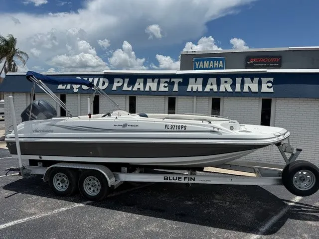 The Image of A 2014 Hurricane 201 Sun Deck Sport boat on a trailer in front of a marine store. - 1